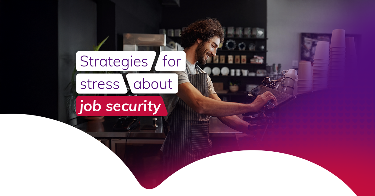 A brown-haired male barista smiles as he makes a cup of coffee at a machine
