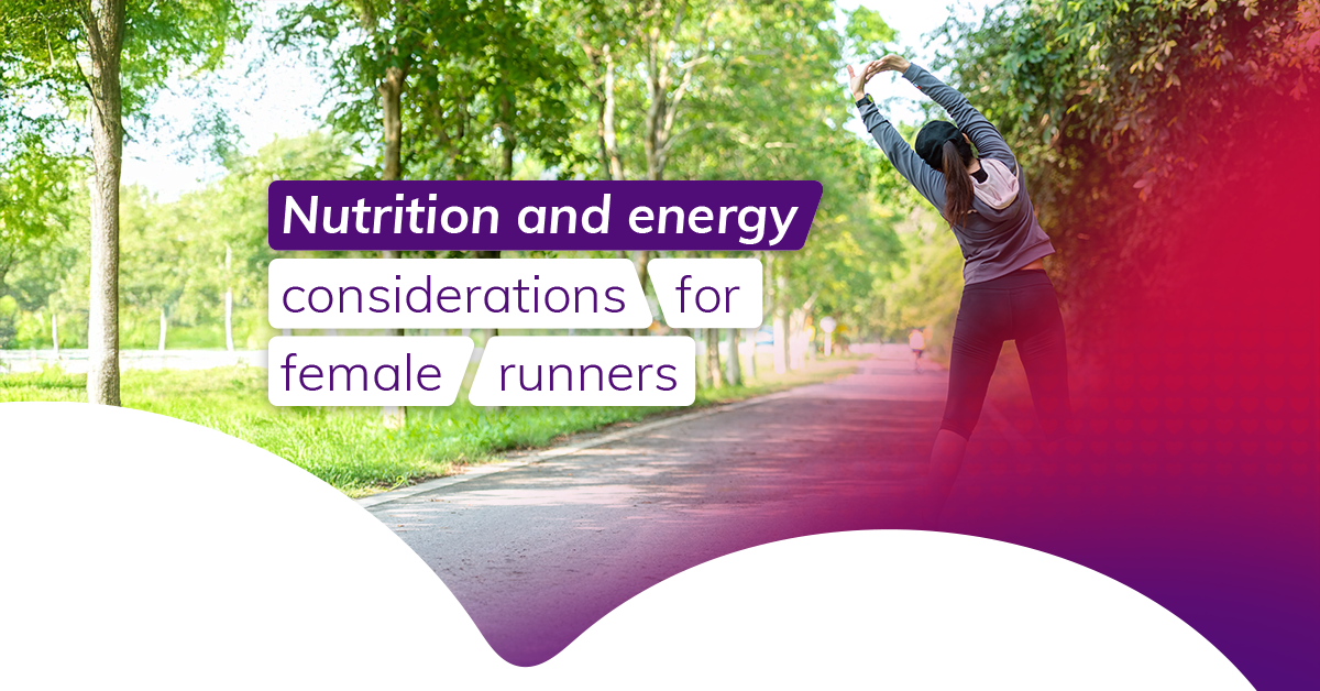 A dark-haired woman wearing workout gear does an overhead stretch in a park, we see her from behind