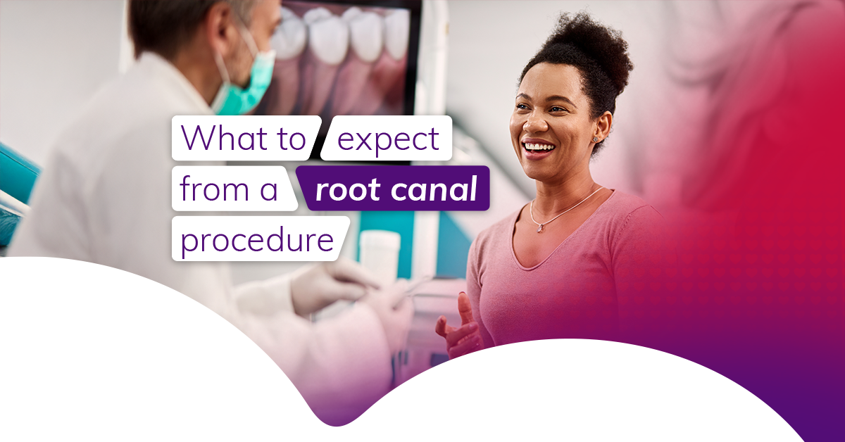 A woman with dark hair tied up sits in a dentist's office, in conversation with a male dentist that we can only see from the side. He wears a white coat and a face mask covering his mouth. 