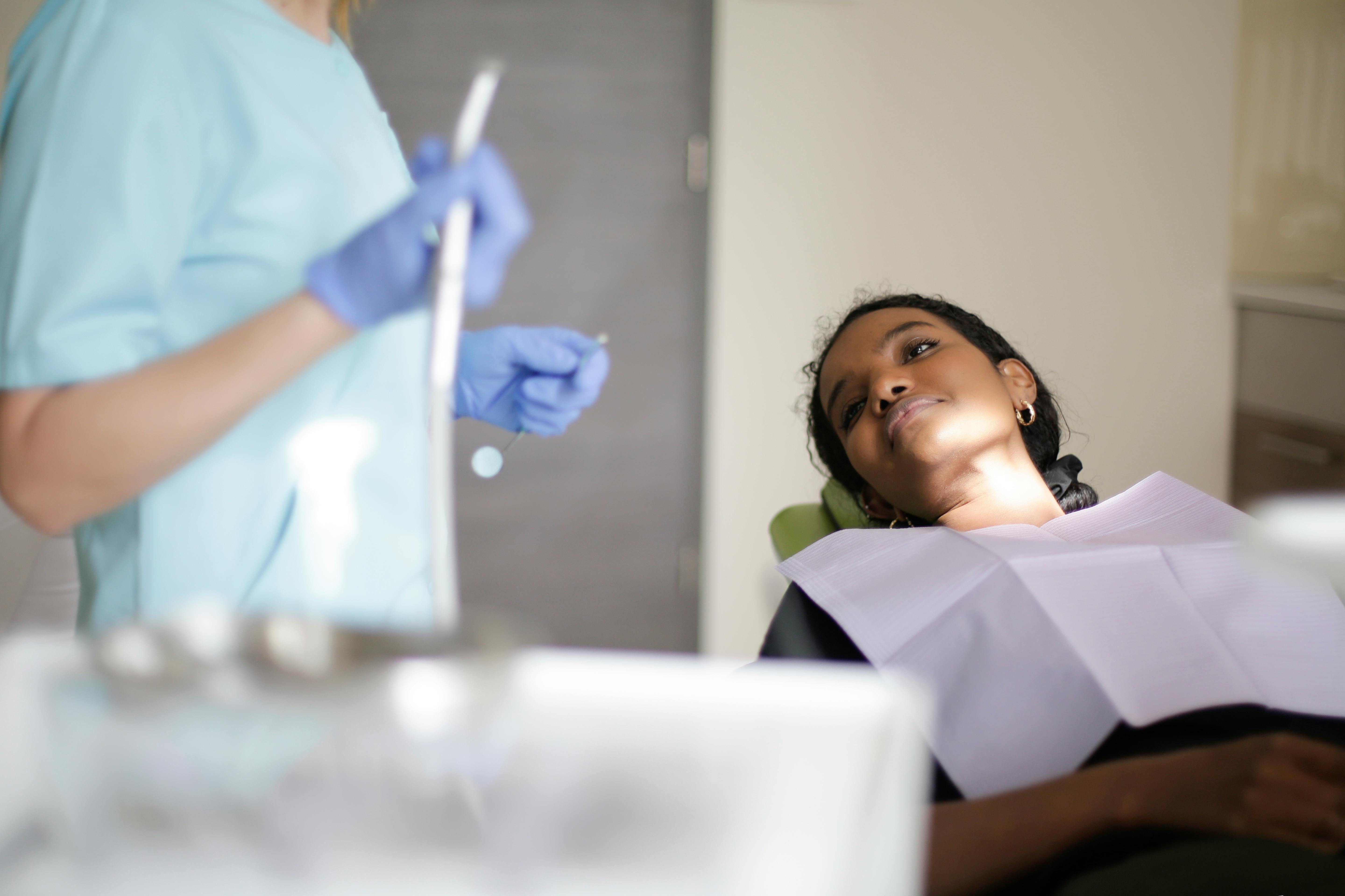 Dentist holding a dental tube with a women waiting to have work begin on her.