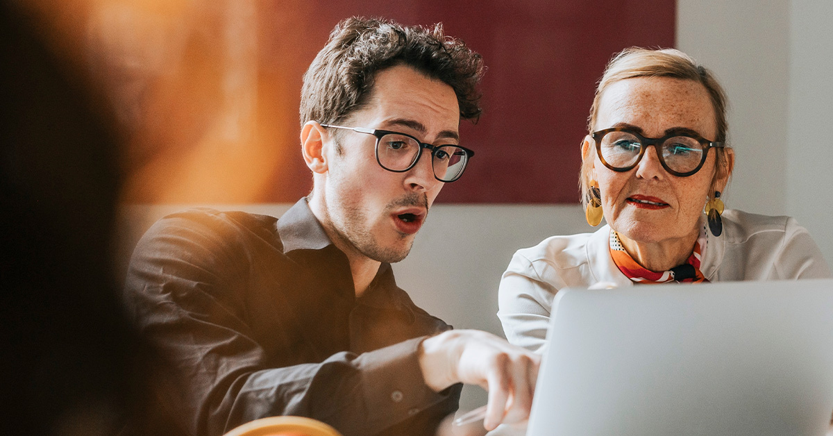 A younger employee showing a document to an older employee
