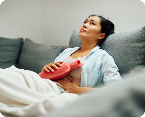 Woman lying on couch with hot water bottle