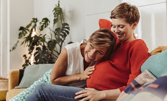 Partner listening to womans pregnant stomach 
